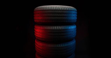 Yeni araba lastikleri. Karanlık arka planda bir grup yol tekeri. Asimetrik lastik dizaynlı yaz lastikleri. Araba sürme kavramı.