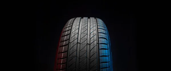 新车轮胎 黑暗背景下的方向盘 夏季轮胎与不对称的胎面设计 驾驶汽车的概念 — 图库照片
