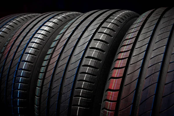 Yeni araba lastikleri. Karanlık arka planda bir grup yol tekeri. Asimetrik lastik dizaynlı yaz lastikleri. Araba sürme kavramı.