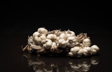 Kokulu sarımsak çelengi koyu arka planda yatıyor. Tarım ve tarım