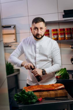 Mutfakta çiğ et pişiren yakışıklı şefin portresi. Bifteği tuzla biberle pişir. Yemek pişirme ve yemek hazırlama kavramı.