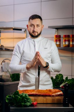Mutfakta çiğ et pişiren yakışıklı şefin portresi. Elinde profesyonel bir mutfak bıçağı var. Yemek pişirme ve yemek hazırlama kavramı