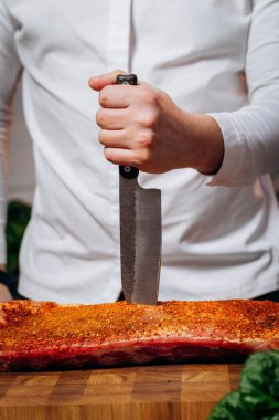 Şef mutfakta çiğ et pişiriyor. Şef profesyonel bir mutfak bıçağı tutuyor. Yemek pişirme ve yemek hazırlama kavramı.