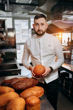 Üniformalı yakışıklı fırında taze ekmek tutuyor.