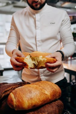 Üniformalı yakışıklı fırıncı fırında taze ekmek kırıyor.