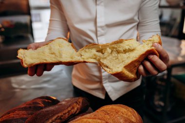 Üniformalı yakışıklı fırıncı fırında taze ekmek kırıyor.