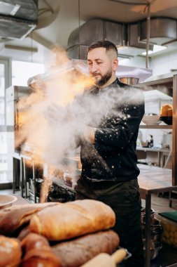 Unlu bir şef. Üniformalı yakışıklı fırıncı fırında ekmek ya da kruvasan pişirdiği için un vuruyor.