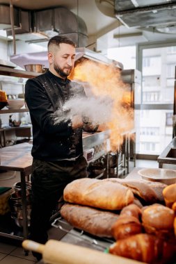 Unlu bir şef. Üniformalı yakışıklı fırıncı fırında ekmek ya da kruvasan pişirdiği için un vuruyor.