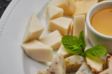 Peynir tabağı: parmesan, çedar, gouda, mozzarella ve diğer koyu arkaplanda beyaz tabakta bal. Lezzetli aperatifler. Üst Manzara. Restoran menüsü için fotoğraf