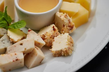 Peynir tabağı: parmesan, çedar, gouda, mozzarella ve diğer koyu arkaplanda beyaz tabakta bal. Lezzetli aperatifler. Üst Manzara. Restoran menüsü için fotoğraf