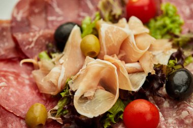 Soğuk et tabağı, jambon, sosis, salam, parma, prosciutto, koyu arkaplanda salam ve zeytin ile kesilmiş domuz pastırması. Et aperatifi, şarap seti, yakın çekim.