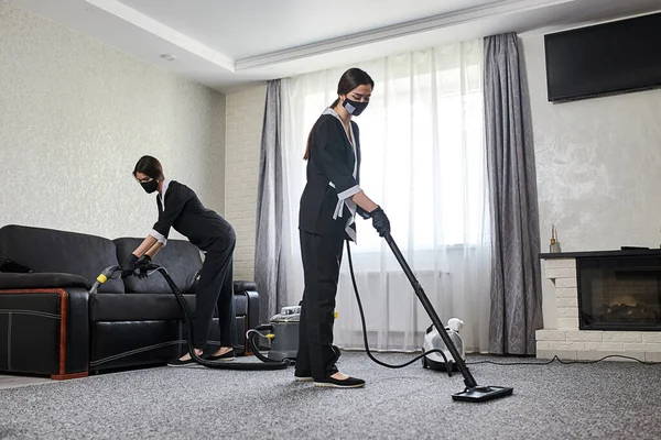 清洁公司的员工使用专业设备从公寓的家具上清除灰尘 家庭主妇用洗衣机和蒸汽吸尘器清洁沙发和地板 — 图库照片