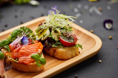 Somon, parma ve pesto soslu çeşitli bruschetta seti. İtalyan antipasti atıştırmalıkları. Koyu arkaplanda küçük sandviçlerin çeşitli karışımları. Restoran menüsü için fotoğraf