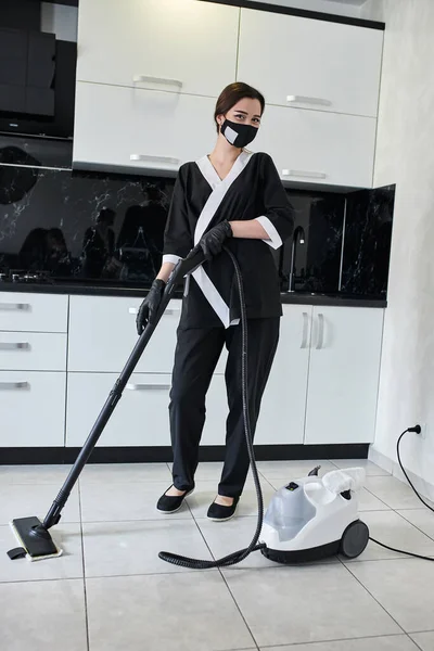 清洁服务公司员工用专业蒸汽清洗机从厨房地板上去除污垢的肖像 — 图库照片