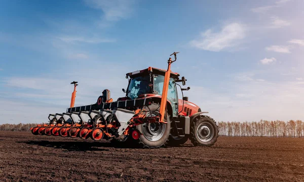 Bahar ekme mevsimi. Traktörlü bir çiftçi tarlasına mısır tohumu ekiyor. İzli ekiciyle mısır ekiyorum. Çiftçilik tohumları. Tarım ve tarım makineleri kavramı.