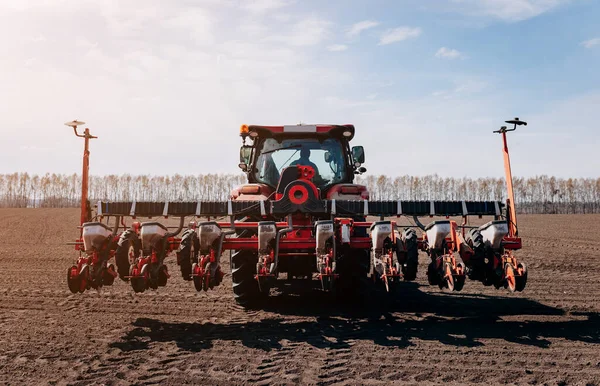 Bahar ekme mevsimi. Traktörlü bir çiftçi tarlasına mısır tohumu ekiyor. İzli ekiciyle mısır ekiyorum. Çiftçilik tohumları. Tarım ve tarım makineleri kavramı.