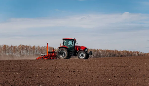 Bahar ekme mevsimi. Traktörlü bir çiftçi tarlasına mısır tohumu ekiyor. İzli ekiciyle mısır ekiyorum. Çiftçilik tohumları. Tarım ve tarım makineleri kavramı.
