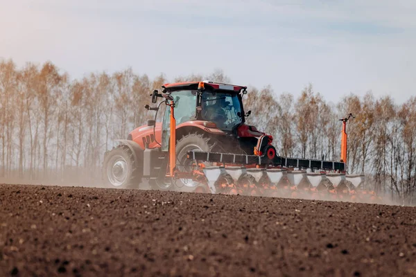Bahar ekme mevsimi. Traktörlü bir çiftçi tarlasına mısır tohumu ekiyor. İzli ekiciyle mısır ekiyorum. Çiftçilik tohumları. Tarım ve tarım makineleri kavramı.