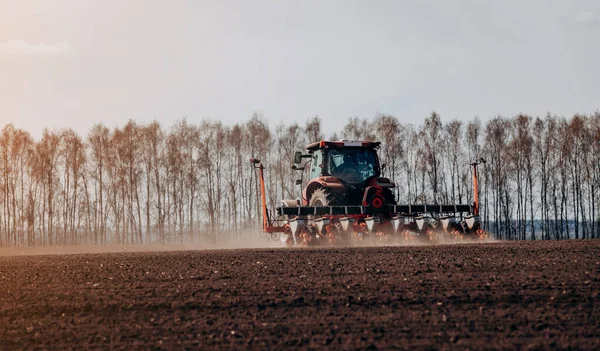 Bahar ekme mevsimi. Traktörlü bir çiftçi tarlasına mısır tohumu ekiyor. İzli ekiciyle mısır ekiyorum. Çiftçilik tohumları. Tarım ve tarım makineleri kavramı.
