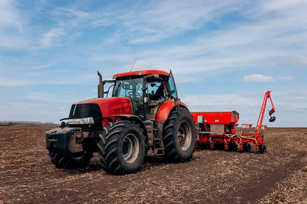 Bahar ekme mevsimi. Traktörlü bir çiftçi tarlasına mısır tohumu ekiyor. İzli ekiciyle mısır ekiyorum. Çiftçilik tohumları. Tarım ve tarım makineleri kavramı.
