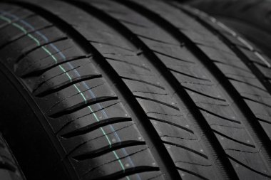 Yeni araba lastikleri. Karanlık arka planda bir grup yol tekeri. Asimetrik lastik dizaynlı yaz lastikleri. Araba sürme kavramı.