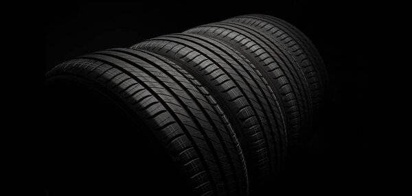 New car tires. Group of road wheels on dark background. Summer Tires with asymmetric tread design. Driving car concept.