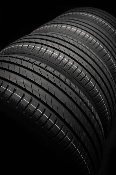 Yeni araba lastikleri. Karanlık arka planda bir grup yol tekeri. Asimetrik lastik dizaynlı yaz lastikleri. Araba sürme kavramı.