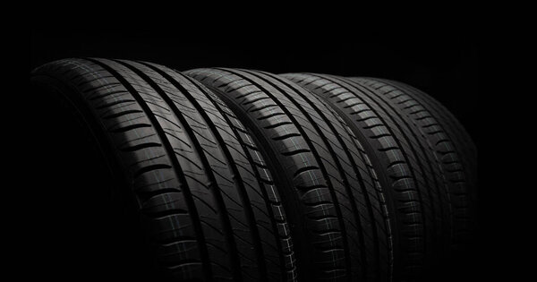 New car tires. Group of road wheels on dark background. Summer Tires with asymmetric tread design. Driving car concept.