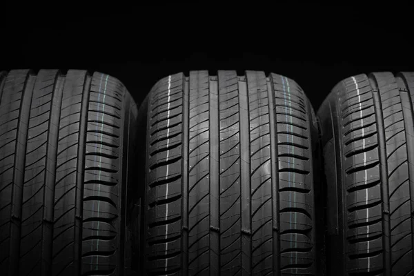 Yeni araba lastikleri. Karanlık arka planda bir grup yol tekeri. Asimetrik lastik dizaynlı yaz lastikleri. Araba sürme kavramı.
