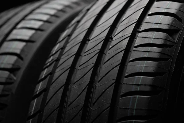 Yeni araba lastikleri. Karanlık arka planda bir grup yol tekeri. Asimetrik lastik dizaynlı yaz lastikleri. Araba sürme kavramı.