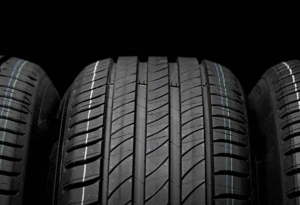 Yeni araba lastikleri. Karanlık arka planda bir grup yol tekeri. Asimetrik lastik dizaynlı yaz lastikleri. Araba sürme kavramı.