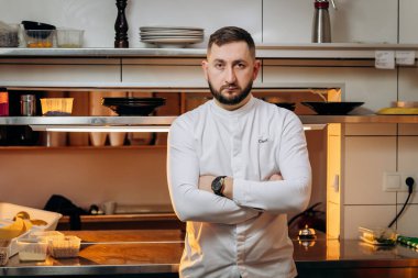 Sakallı beyaz erkek aşçının portresi. Restoranın mutfağında beyaz üniformalı aşçı.