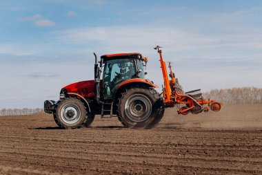 Bahar ekme mevsimi. Traktörlü bir çiftçi tarlasına mısır tohumu ekiyor. İzli ekiciyle mısır ekiyorum. Çiftçilik tohumları. Tarım ve tarım makineleri kavramı.