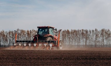 Bahar ekme mevsimi. Traktörlü bir çiftçi tarlasına mısır tohumu ekiyor. İzli ekiciyle mısır ekiyorum. Çiftçilik tohumları. Tarım ve tarım makineleri kavramı.