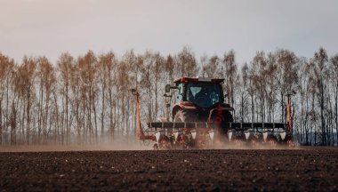 Bahar ekme mevsimi. Traktörlü bir çiftçi tarlasına mısır tohumu ekiyor. İzli ekiciyle mısır ekiyorum. Çiftçilik tohumları. Tarım ve tarım makineleri kavramı.