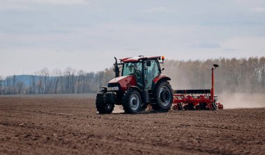 Bahar ekme mevsimi. Traktörlü bir çiftçi tarlasına mısır tohumu ekiyor. İzli ekiciyle mısır ekiyorum. Çiftçilik tohumları. Tarım ve tarım makineleri kavramı.