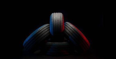 Yeni araba lastikleri. Karanlık arka planda bir grup yol tekeri. Asimetrik lastik dizaynlı yaz lastikleri. Araba sürme kavramı.