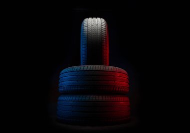 Yeni araba lastikleri. Karanlık arka planda bir grup yol tekeri. Asimetrik lastik dizaynlı yaz lastikleri. Araba sürme kavramı.