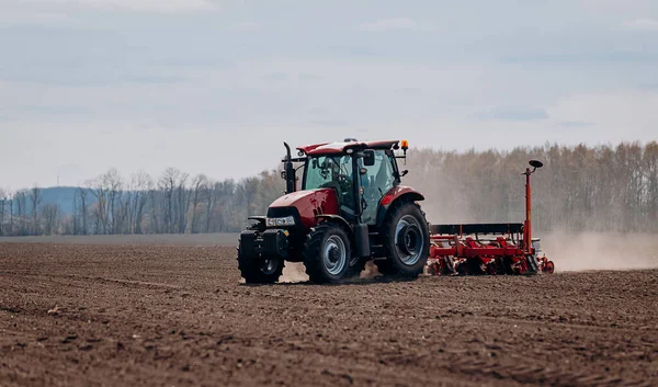 Bahar ekme mevsimi. Traktörlü bir çiftçi tarlasına mısır tohumu ekiyor. İzli ekiciyle mısır ekiyorum. Çiftçilik tohumları. Tarım ve tarım makineleri kavramı.
