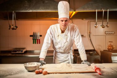 Profesyonel pasta şefi ekmek, İtalyan makarnası veya pizza yapmak için profesyonel bir mutfakta un ile hamur hazırlıyor. Yemek pişirme kavramı
