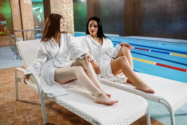 健康的生活方式的概念 身穿浴衣的年轻漂亮姑娘们在游泳池边的甲板椅子上的豪华温泉里放松一下 健康主题 — 图库照片