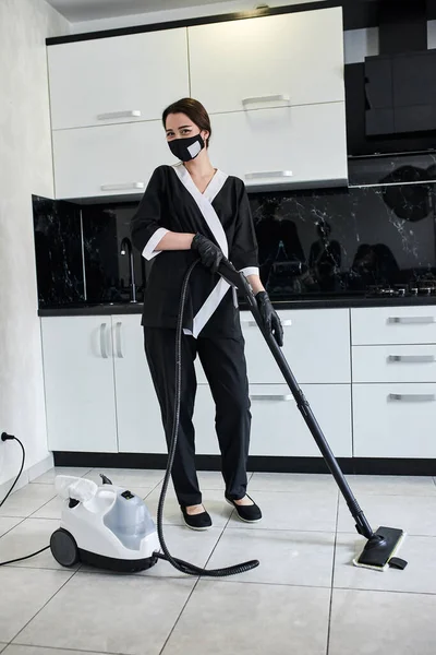 清洁服务公司员工用专业蒸汽清洗机从厨房地板上去除污垢的肖像 — 图库照片