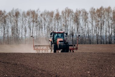 Vinnitsa, Ukrayna - 20 Nisan 2022: Bahar ekimi mevsimi. Traktörlü bir çiftçi tarlasına mısır tohumu ekiyor. İzli ekiciyle mısır ekiyorum. Çiftçilik tohumları