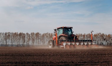 Vinnitsa, Ukrayna - 20 Nisan 2022: Bahar ekimi mevsimi. Traktörlü bir çiftçi tarlasına mısır tohumu ekiyor. İzli ekiciyle mısır ekiyorum. Çiftçilik tohumları