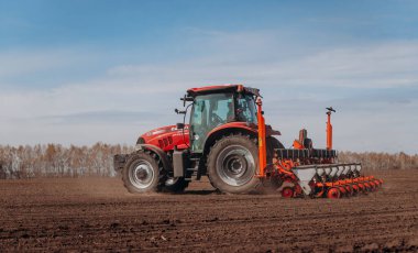 Vinnitsa, Ukrayna - 20 Nisan 2022: Bahar ekimi mevsimi. Traktörlü bir çiftçi tarlasına mısır tohumu ekiyor. İzli ekiciyle mısır ekiyorum. Çiftçilik tohumları