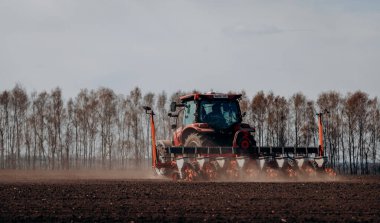 Vinnitsa, Ukrayna - 20 Nisan 2022: Bahar ekimi mevsimi. Traktörlü bir çiftçi tarlasına mısır tohumu ekiyor. İzli ekiciyle mısır ekiyorum. Çiftçilik tohumları