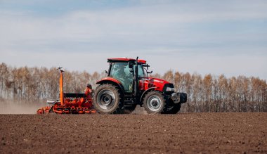 Vinnitsa, Ukraine - April 20, 2022: Spring sowing season. Farmer with a tractor sows corn seeds on his field. Planting corn with trailed planter. Farming seeding