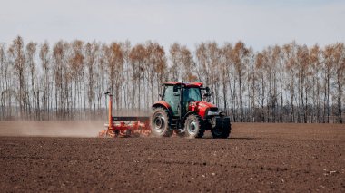 Vinnitsa, Ukrayna - 20 Nisan 2022: Bahar ekimi mevsimi. Traktörlü bir çiftçi tarlasına mısır tohumu ekiyor. İzli ekiciyle mısır ekiyorum. Çiftçilik tohumları
