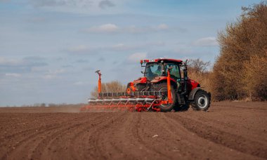 Vinnitsa, Ukrayna - 20 Nisan 2022: Bahar ekimi mevsimi. Traktörlü bir çiftçi tarlasına mısır tohumu ekiyor. İzli ekiciyle mısır ekiyorum. Çiftçilik tohumları