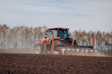 Vinnitsa, Ukraine - April 20, 2022: Spring sowing season. Farmer with a tractor sows corn seeds on his field. Planting corn with trailed planter. Farming seeding